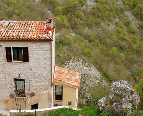 a house with a rock next to a mountain at Casa Vacanze L'arco di Fondarca n.16 in Cagli