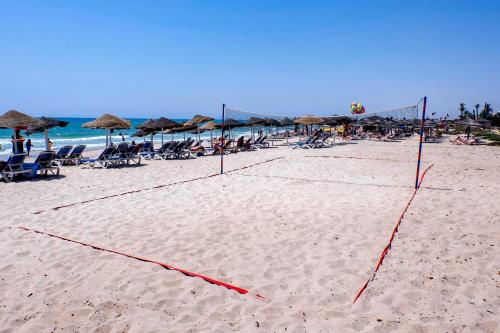 a volleyball net on a beach with chairs and umbrellas at Medina Belisaire And Thalasso in Hammamet
