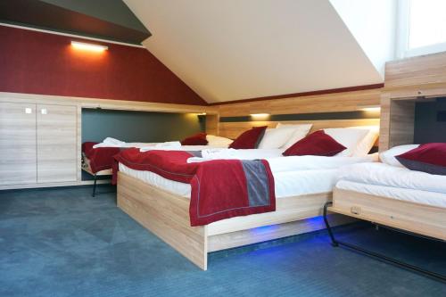 a bedroom with three beds with red and white sheets at Villa Winterpol in Karpacz