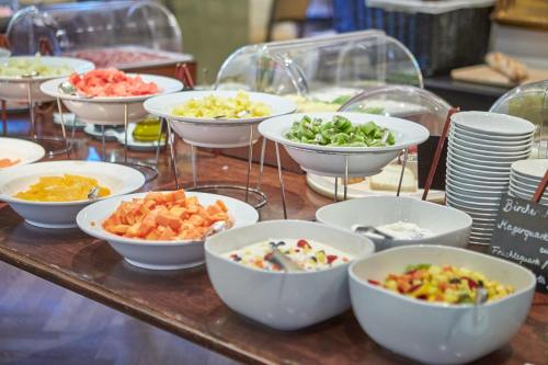 a table topped with bowls of different types of food at Hotel Nassauer Hof in Wiesbaden