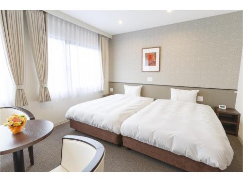 a hotel room with a large bed and a table at Hotel Amabile Maizuru in Maizuru