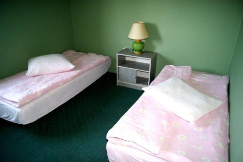 a bedroom with two beds and a table with a lamp at Hotel Holidays in Słubice