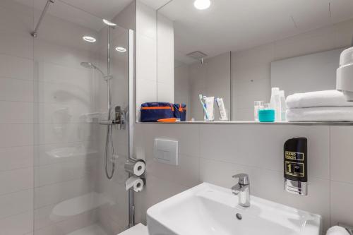uma casa de banho branca com um chuveiro e um lavatório. em Serways Hotel Spessart em Rohrbrunn