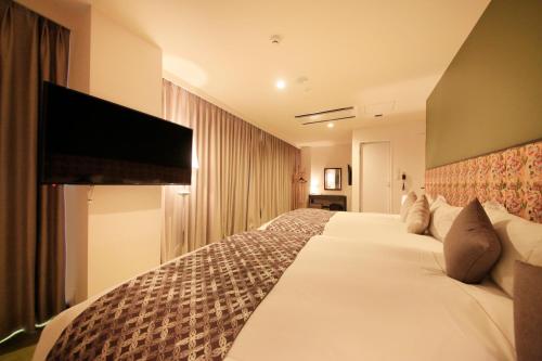 a hotel room with two beds and a flat screen tv at Centurion Hotel&Spa Ueno Station in Tokyo