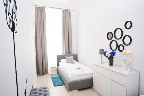 ein weißes Zimmer mit einem Bett und einem Spiegel in der Unterkunft Apartament Pod Kopernikiem II in Toruń