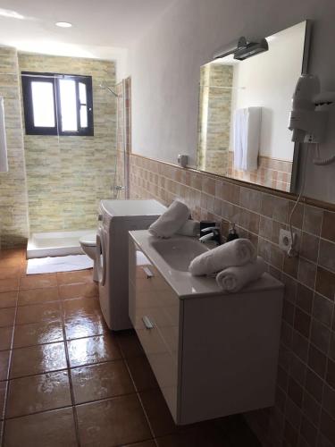 a bathroom with a sink and a toilet and a mirror at Apartamento los Rostros in La Santa