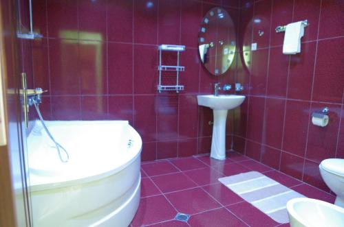 a bathroom with a tub and a sink and a toilet at Hotel Kiparisi in Kobuleti