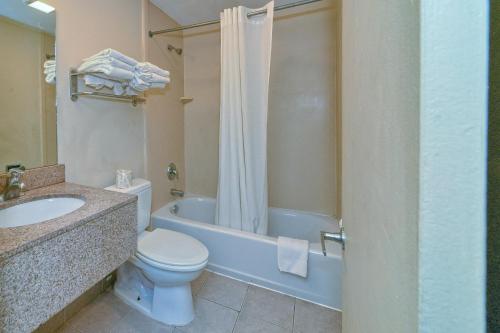 a bathroom with a toilet and a sink and a tub at Red Carpet Inn - Stamford in Stamford