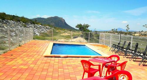 a swimming pool with red chairs and a table at Casas y Cuevas El Solins in Las Casicas