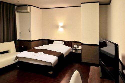 una habitación de hotel con 2 camas y una silla en Hotel Saint Paul Nagasaki, en Nagasaki