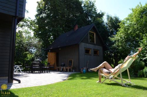 a woman laying in a lawn chair in front of a house at Pilava in Roja