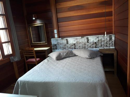 a bedroom with a bed with a stone wall at Pousada Vale Do Comandante in Macacos