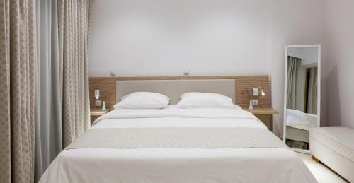 a bedroom with a large white bed and a mirror at Zephyros Hotel in Myrties