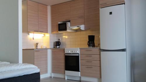 a kitchen with wooden cabinets and a white refrigerator at New nice apartment in Vaasa