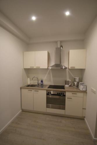 eine Küche mit weißen Schränken und einem Herd mit Backofen in der Unterkunft Altstadt Apartment in Bremen