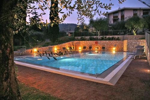 ein großer Pool in einem Garten in der Nacht in der Unterkunft Residence Uliveto e Casa Anna in Garda
