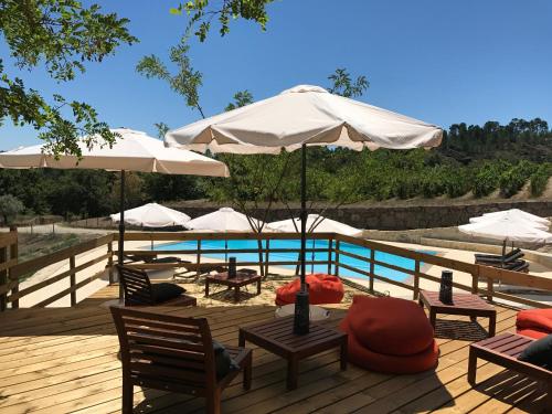 a deck with chairs and umbrellas and a pool at Quinta do Medronheiro Hotel Rural in Viseu