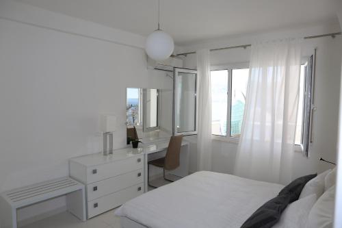 Habitación blanca con cama, escritorio y ventana en White Residence Luxury Apartments, en Sarandë