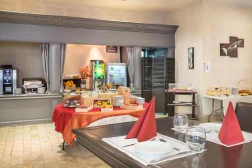 Una cocina con una mesa con servilletas rojas. en Hôtel & Spa du Domaine des Thômeaux, The Originals Relais, en Mosnes