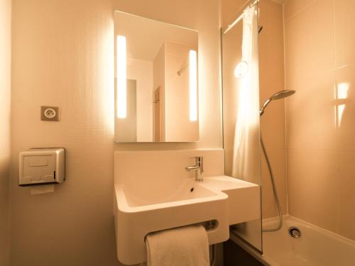 a bathroom with a sink and a mirror and a shower at B&B HOTEL Alencon Nord in Alençon