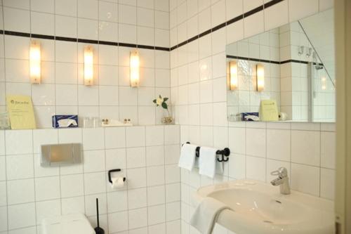 ein weißes Badezimmer mit einem Waschbecken und einem Spiegel in der Unterkunft Hotel am Park in Dinslaken