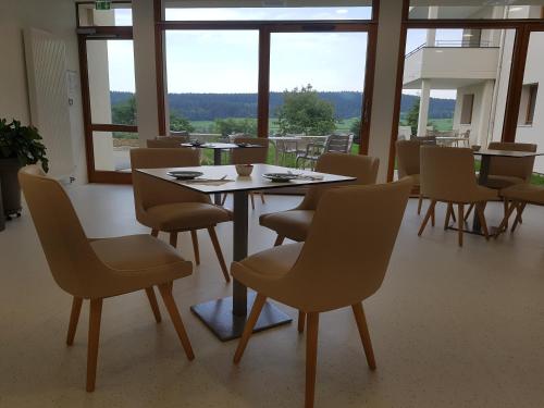 a dining room with a table and chairs and windows at Hotel Spa Les Rives Sauvages in Malbuisson