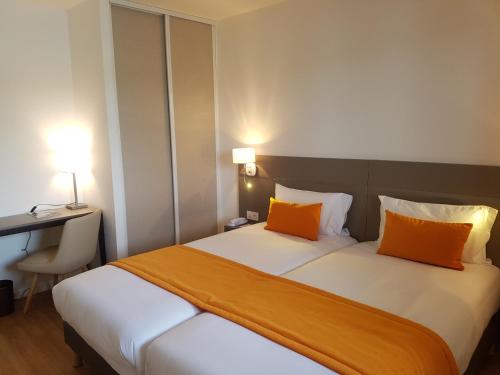 two beds in a hotel room with two orange pillows at Hotel Spa Les Rives Sauvages in Malbuisson