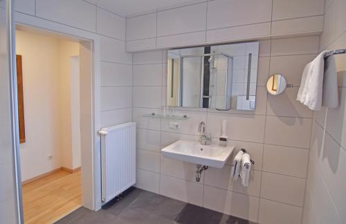 a white bathroom with a sink and a mirror at Hotel Ausseerland in Bad Mitterndorf