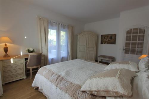 a white bedroom with a bed and a desk and a window at Aux charmes de grasse in Grasse