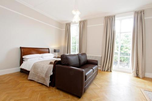 a bedroom with a bed and a leather chair at Apartments At Marylebone in London