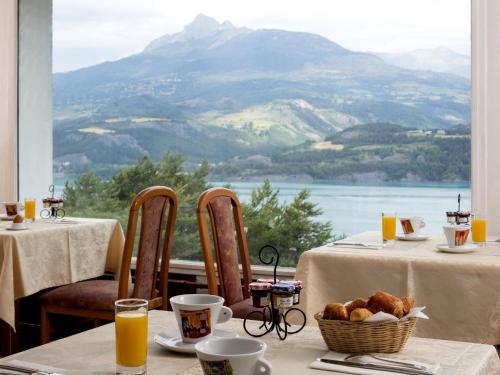 una mesa con una cesta de comida y vistas a la montaña en Logis Hotel Eden Lac en Savines
