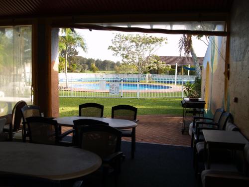 a patio with tables and chairs and a swimming pool at The Nambucca Motel in Nambucca Heads