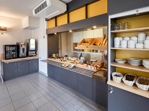 une grande cuisine avec des placards bleus et des assiettes sur des étagères dans l'établissement B&B HOTEL Boulogne-sur-Mer Saint-Martin, à Saint-Martin-Boulogne