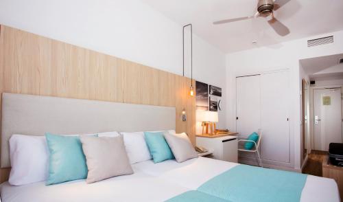1 dormitorio con 1 cama con almohadas azules y blancas en Hotel Monterrey Roses by Pierre & Vacances, en Roses