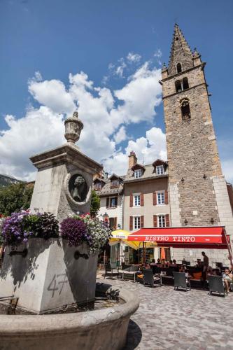 a fountain in front of a building with a tower at La Grande Eperviere in Barcelonnette