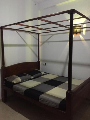 a wooden bed with a black and white canopy at Rice Field View Home Stay in Tangalle