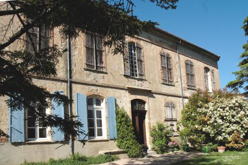 un antiguo edificio de ladrillo con persianas azules y una puerta en Château de Vallègue, en Vallègue
