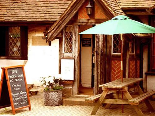 uma mesa de piquenique com um guarda-chuva em frente a um edifício em Chequers Inn Hotel em Forest Row