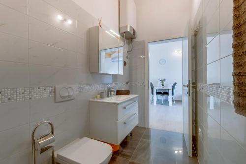 a white bathroom with a sink and a toilet at Apartments Relax in Veli Lošinj