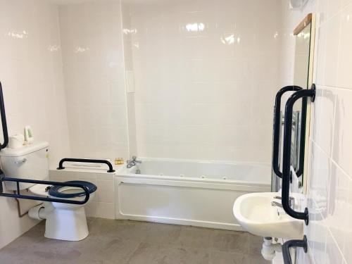 a bathroom with a tub and a toilet and a sink at The Beach Motel in Trearddur