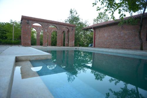 a swimming pool with a brick building in the background at Chateau Chikovani in Gordi