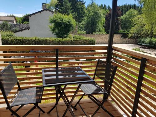 a glass table and two chairs on a deck at Logis SPA Hotel Restaurant De La Poste in Tence