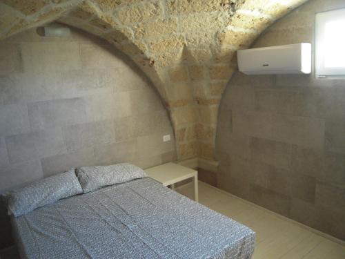 a bedroom with a bed in a stone wall at deliziosa antica dimora in Calimera