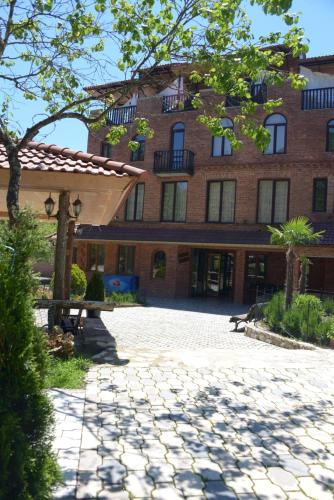 a large red brick building with a stone courtyard at Chateau Chikovani in Gordi