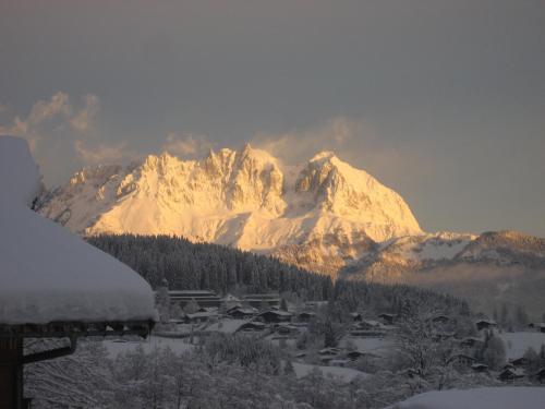 a snow covered mountain with a village in front of it at Pension Hinterseer in Kitzbühel