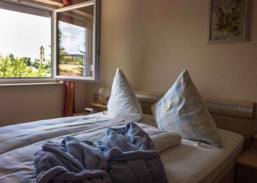 um quarto com uma cama com almofadas e uma janela em Ferienwohnungen Anna em Bad Birnbach