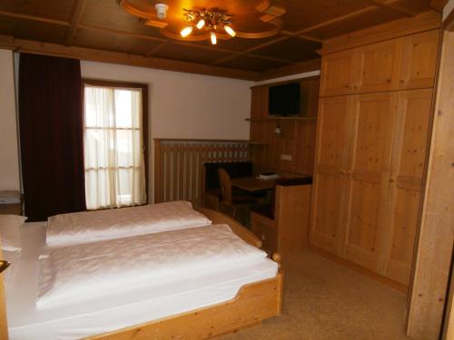 a bedroom with two beds and a desk at Piccolo Hotel Gurschler in Maso Corto