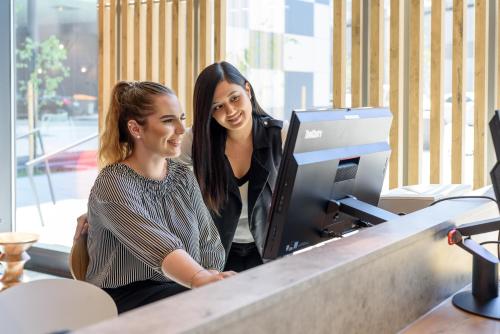 two women standing at a desk in front of a computer at ibis Wien Hauptbahnhof in Vienna
