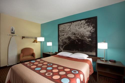 a hotel room with a bed and a painting on the wall at Super 8 by Wyndham Mount Vernon, IL in Mount Vernon