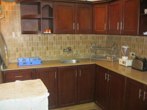 a kitchen with wooden cabinets and a sink at Three-Bedroom Apartment at Nazlet El Semman in Cairo